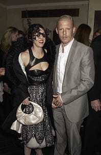 ISABELLA BLOW L'ECLETTICA MUSA DEL FASHION 7 isabella blow e alexander mcqueen a una festa, una in un abito nero con dettagli bianchi e l'altra in un completo grigio chiaro.